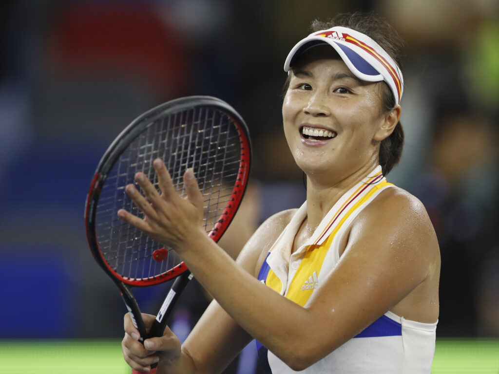 Peng shuai with a smile holding racket in a match 